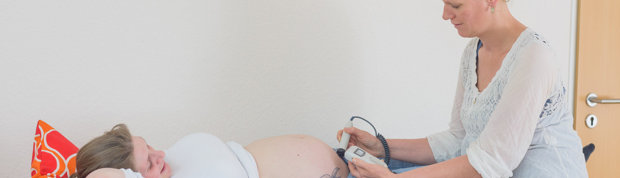 Eine Hebamme führt eine Ultraschalluntersuchung an einer Schwangeren durch.